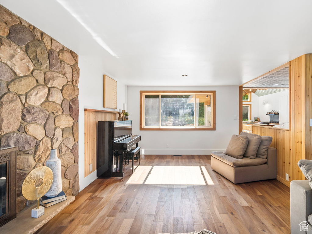 Living room with a stone fireplace, wooden walls, and wood-type flooring