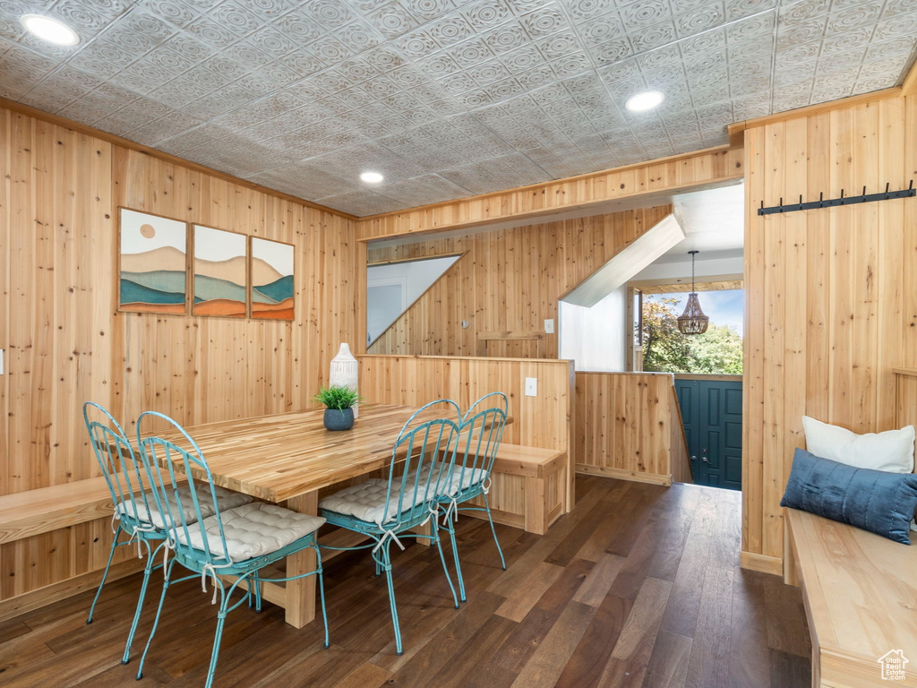 Dining space with dark hardwood / wood-style floors and wooden walls