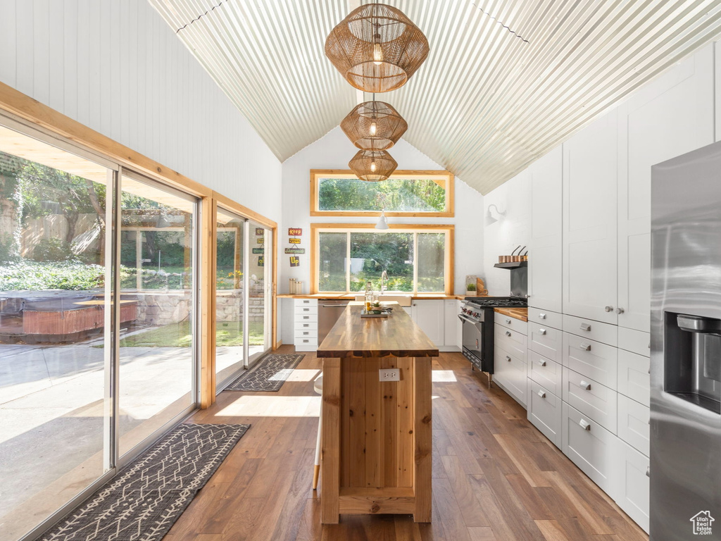 Interior space with wooden counters, appliances with stainless steel finishes, white cabinetry, and hardwood / wood-style flooring