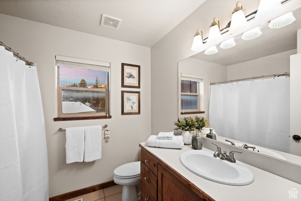 Bathroom featuring tile flooring, toilet, and vanity with extensive cabinet space