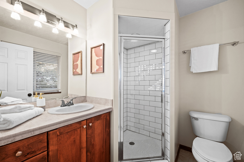 Bathroom featuring an enclosed shower, vanity, and toilet