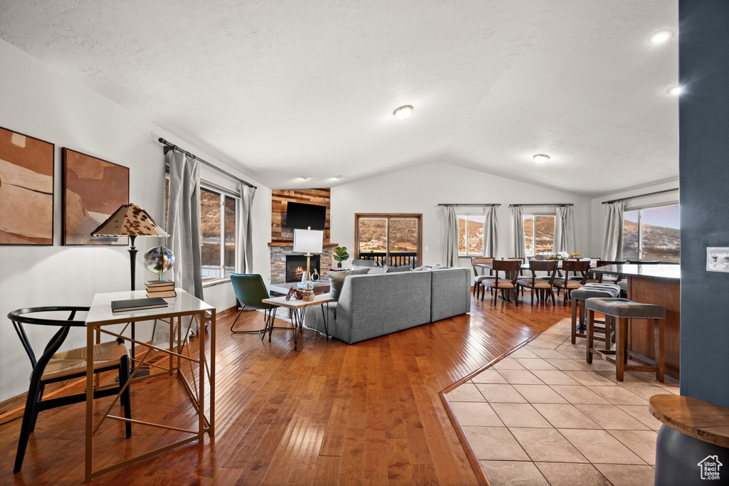 Living room featuring a stone fireplace, vaulted ceiling, and light wood-type flooring