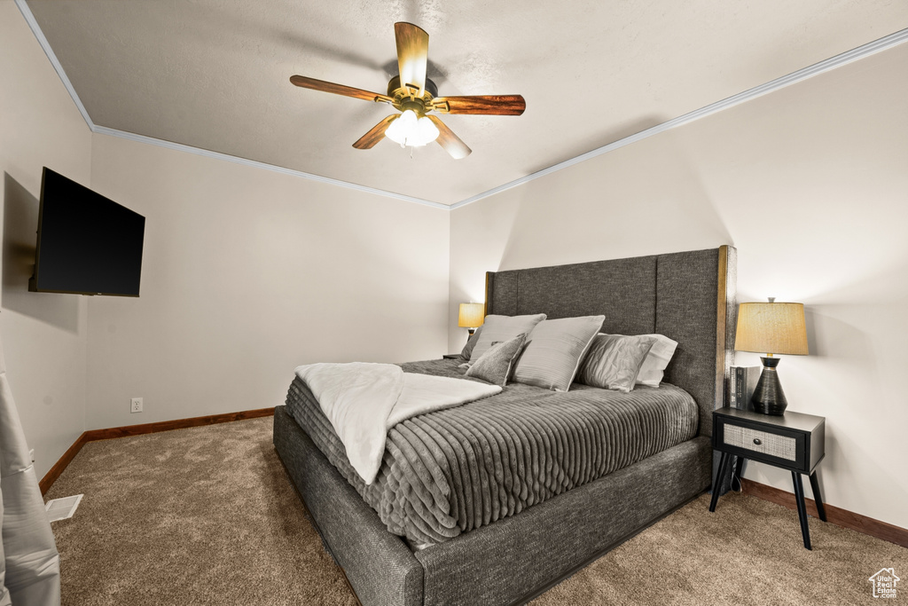 Carpeted bedroom featuring ornamental molding and ceiling fan