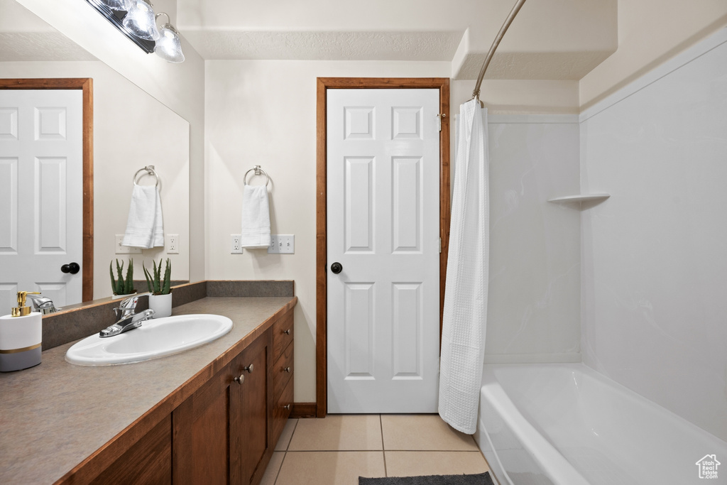 Bathroom featuring shower / bathtub combination with curtain, tile flooring, and oversized vanity