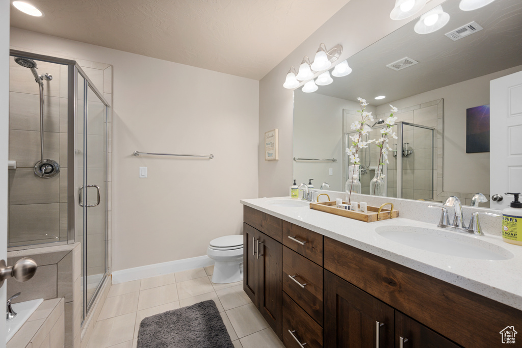 Full bathroom featuring dual sinks, tile flooring, separate shower and tub, toilet, and large vanity