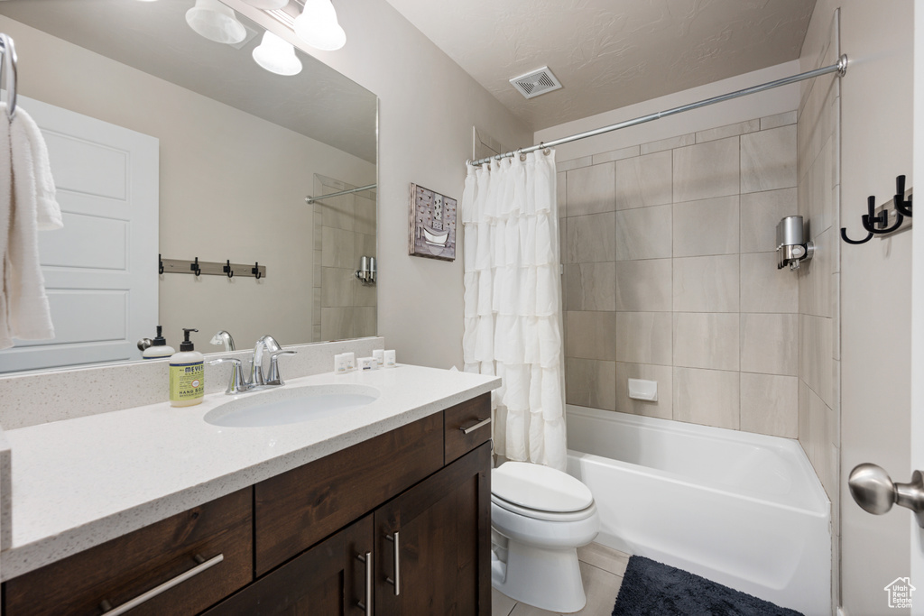 Full bathroom with tile flooring, shower / bath combo, vanity, and toilet