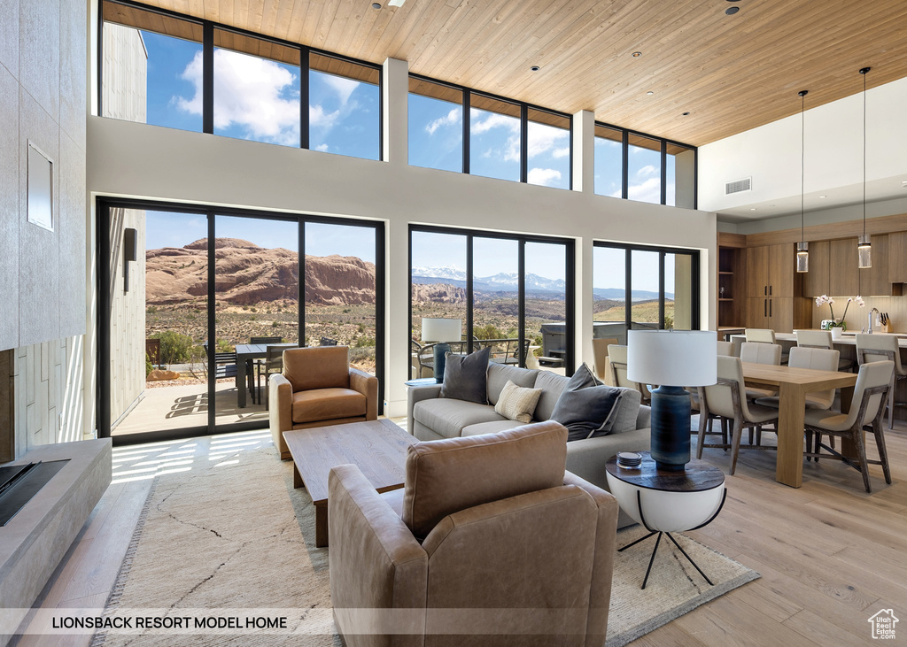 Living room with a mountain view, light hardwood / wood-style flooring, a towering ceiling, and wood ceiling