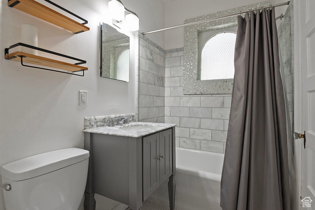 Full bathroom with shower / bath combo, a wealth of natural light, toilet, and large vanity