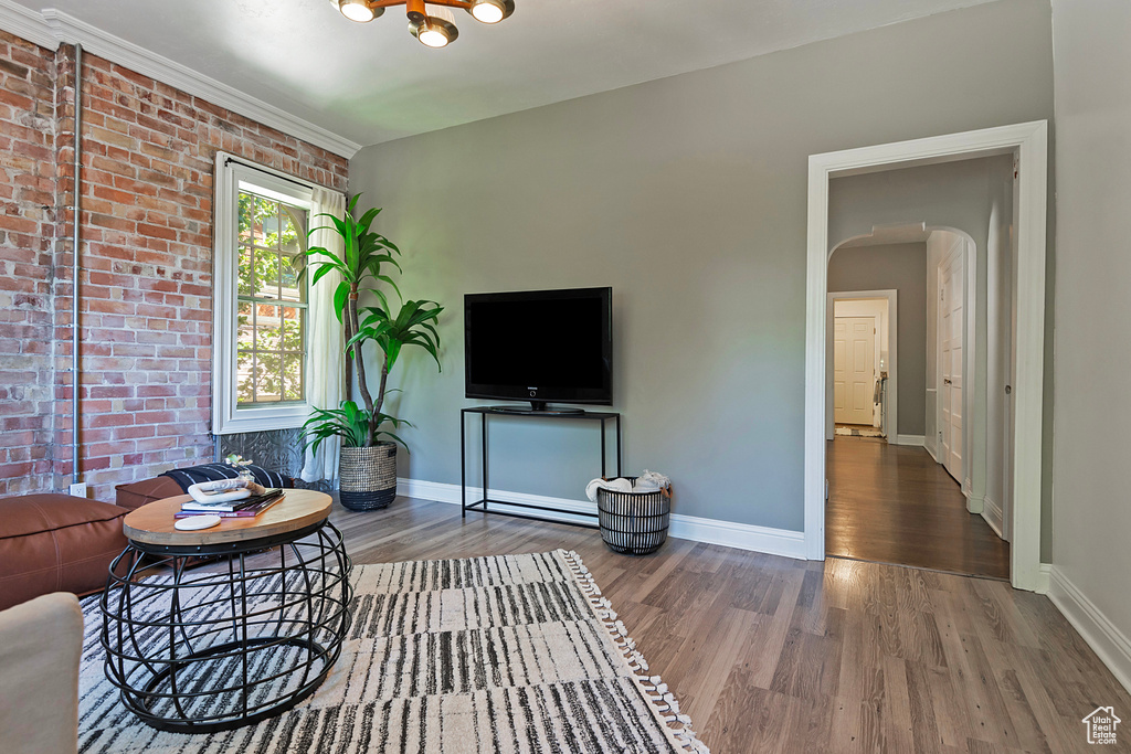 Living room with brick wall and hardwood / wood-style flooring