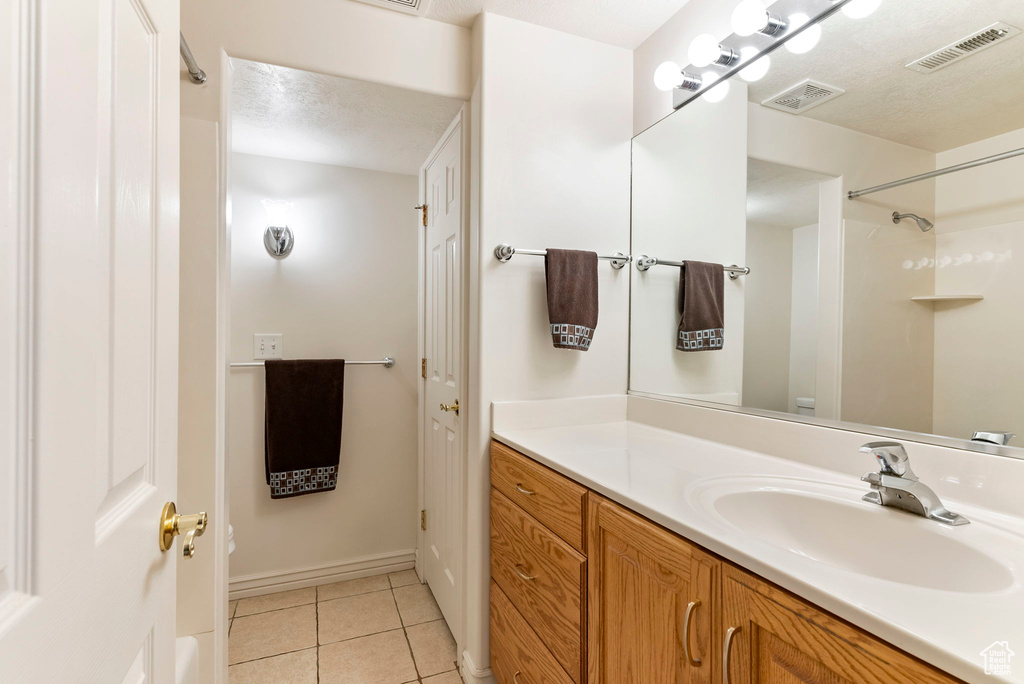 Bathroom with tile flooring, oversized vanity, and a textured ceiling