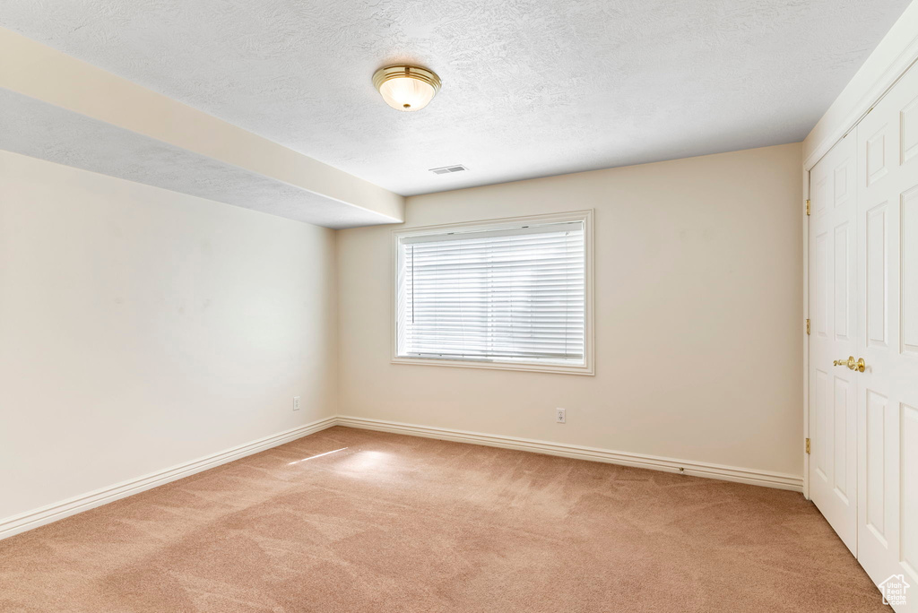 Carpeted spare room with a textured ceiling