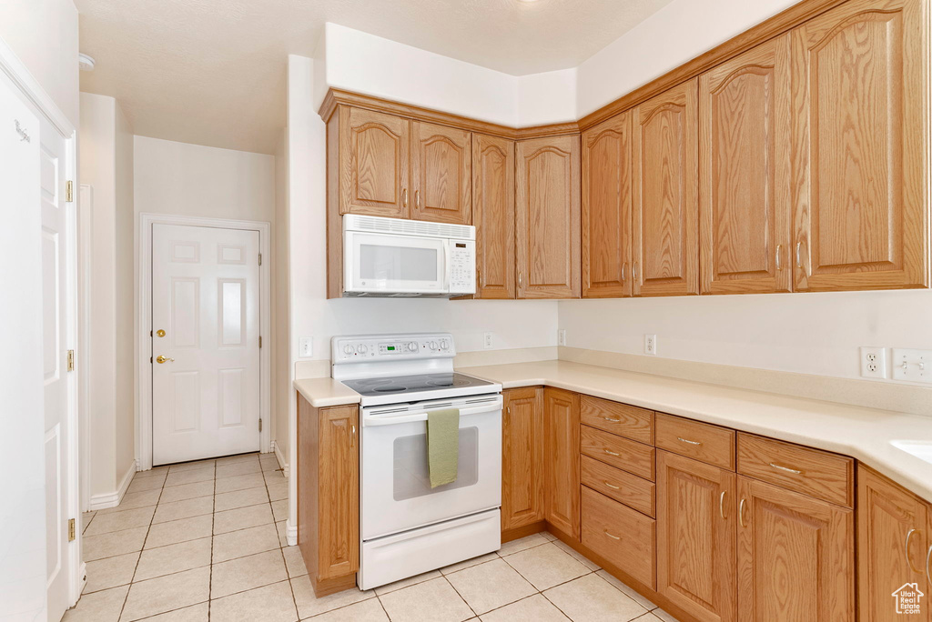 Kitchen featuring white appliances and light tile floors