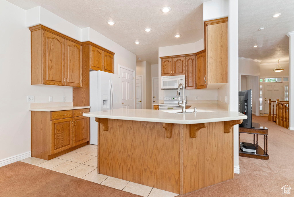 Kitchen featuring light carpet, white appliances, a kitchen breakfast bar, and sink