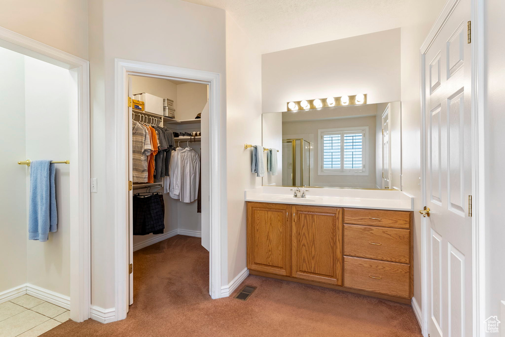 Bathroom with tile flooring, an enclosed shower, and vanity