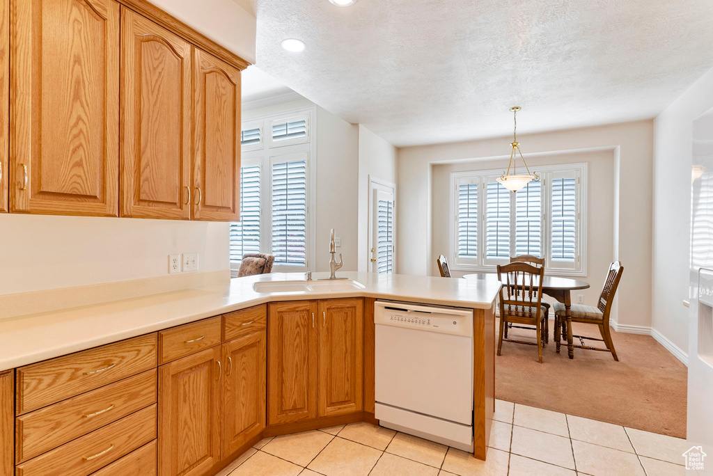 Kitchen featuring a textured ceiling, white dishwasher, sink, light tile floors, and pendant lighting