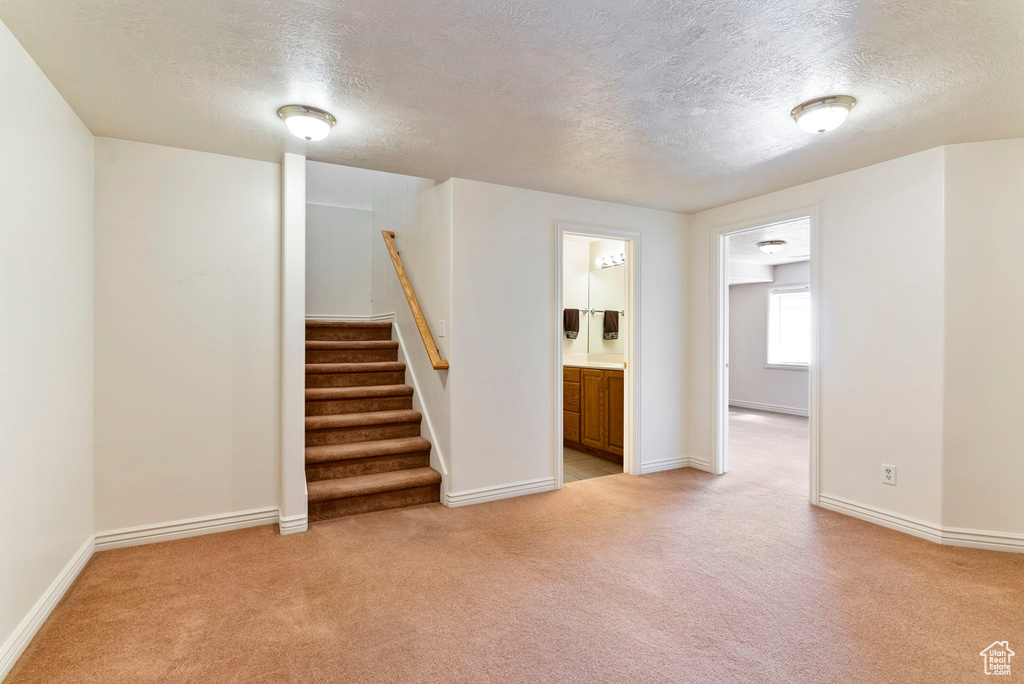 Empty room with light carpet and a textured ceiling