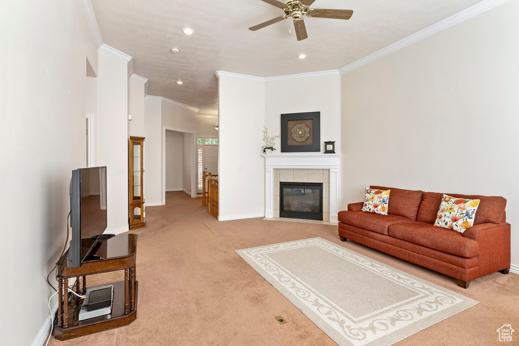 Living room with light carpet, ornamental molding, a tile fireplace, and ceiling fan