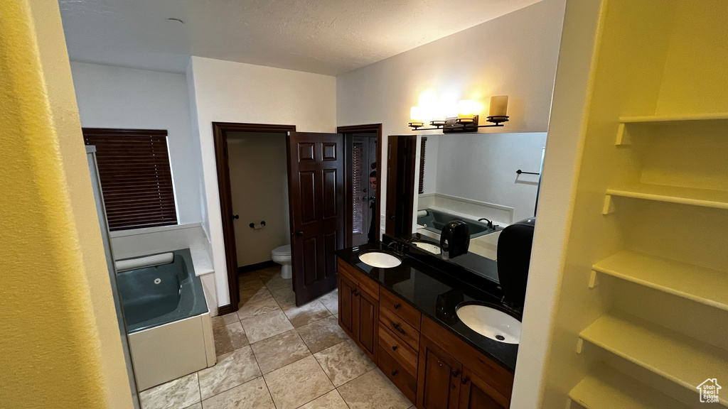 Bathroom featuring tile floors, toilet, and double sink vanity