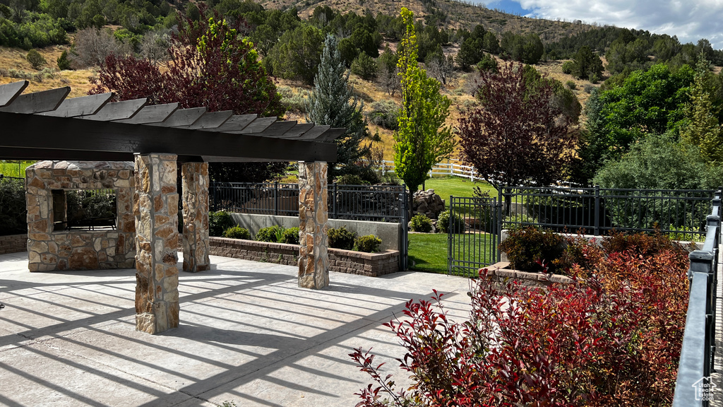 View of patio featuring a pergola and an outdoor stone fireplace