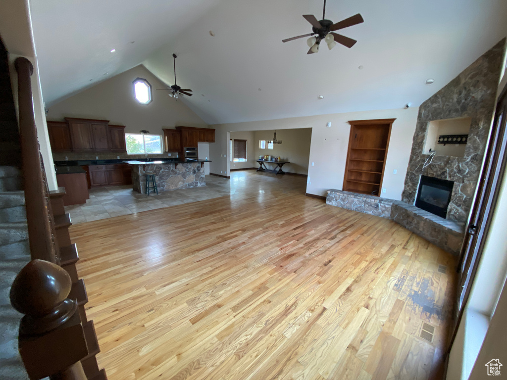 Unfurnished living room with high vaulted ceiling, ceiling fan, and light hardwood / wood-style flooring