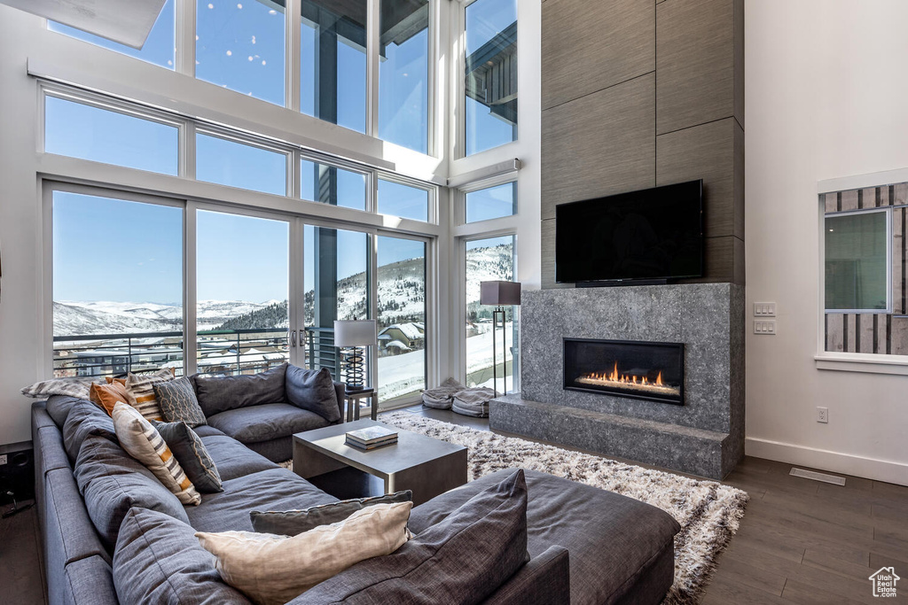 Living room with dark wood-type flooring, a towering ceiling, a mountain view, and a high end fireplace