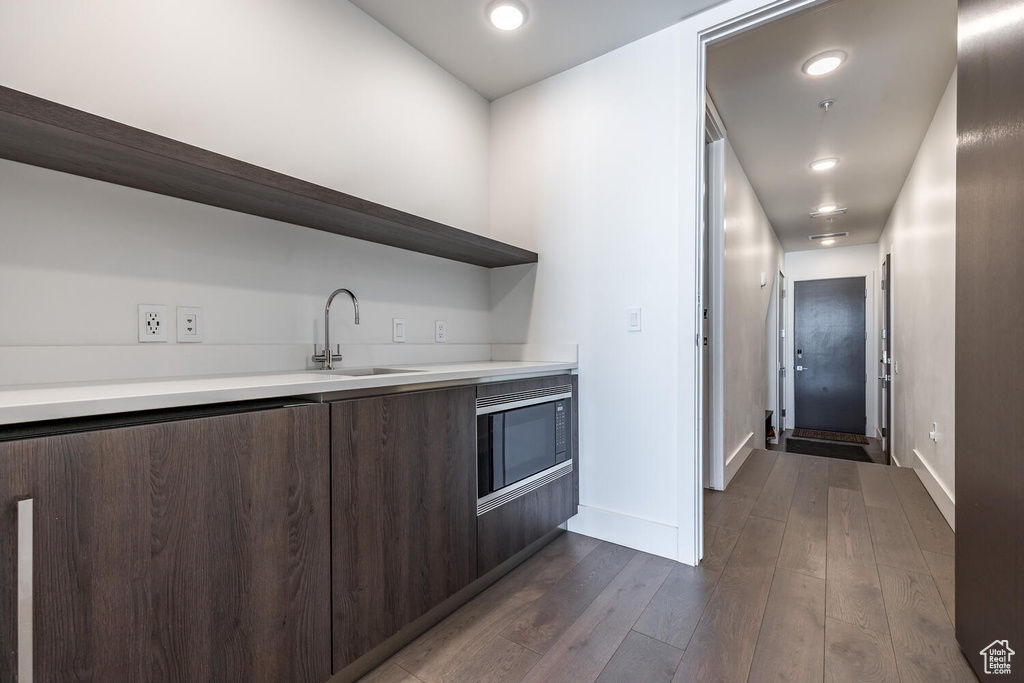 Kitchen featuring dark wood-type flooring, sink, dark brown cabinets, and built in microwave