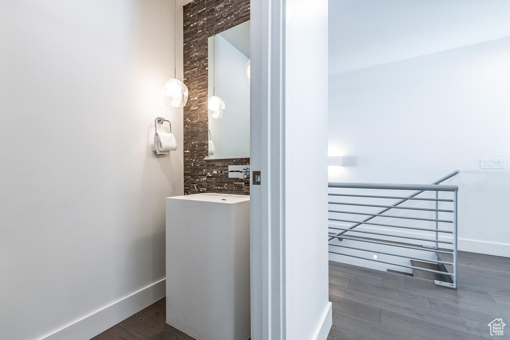 Bathroom with tasteful backsplash, large vanity, hardwood / wood-style flooring, and brick wall