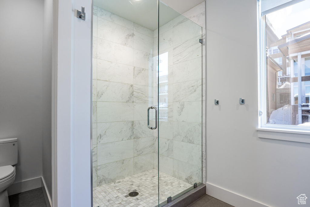 Bathroom with walk in shower, tile flooring, and toilet