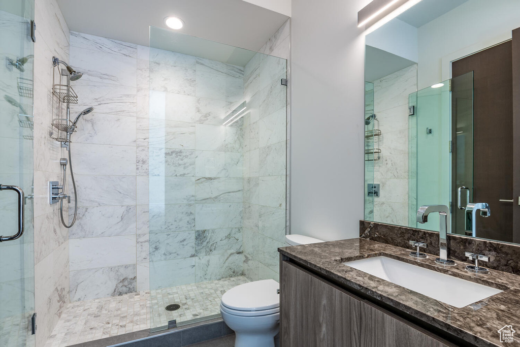 Bathroom with an enclosed shower, vanity, and toilet