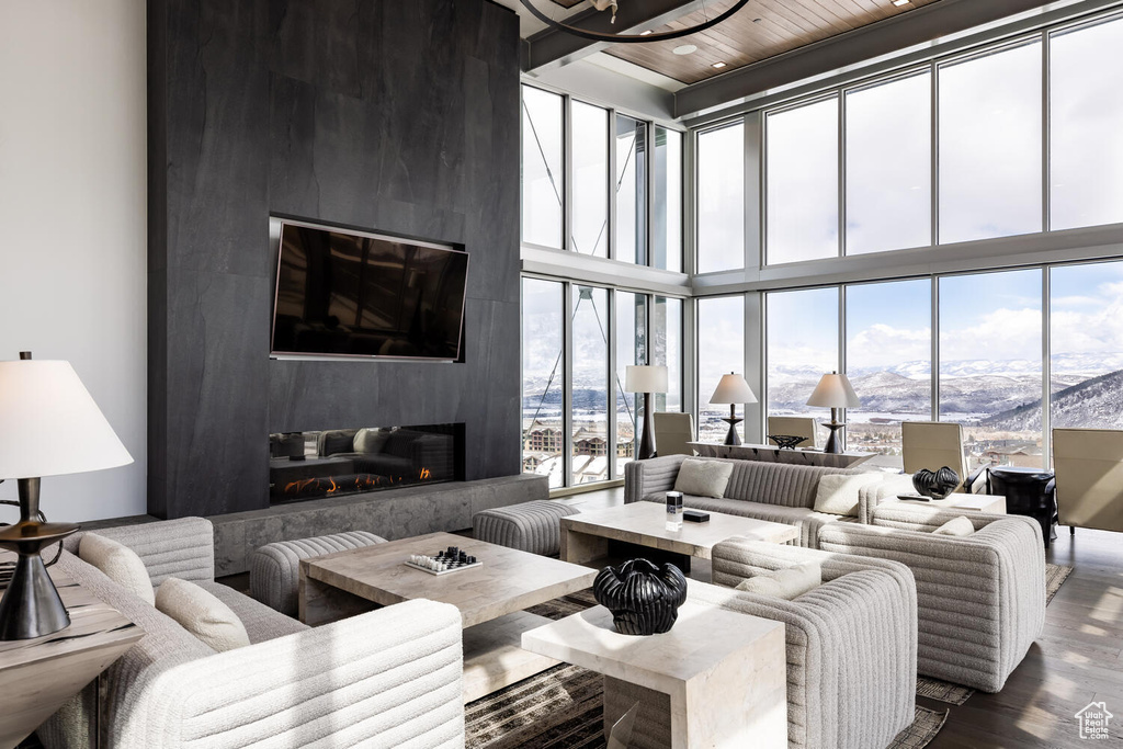 Living room featuring a towering ceiling, plenty of natural light, a fireplace, and dark hardwood / wood-style floors