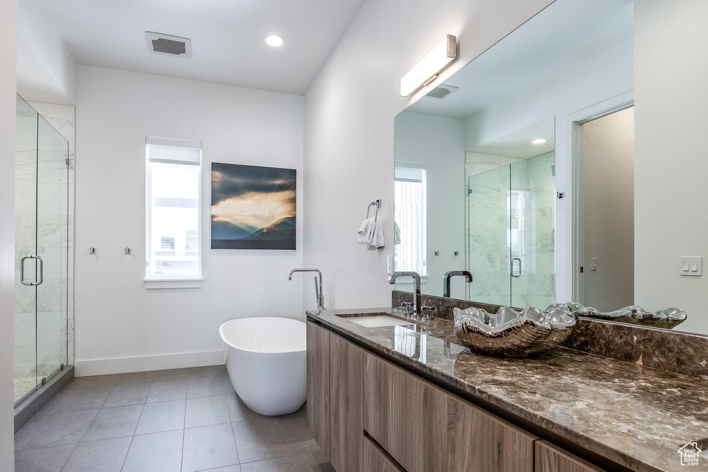 Bathroom with tile flooring, vanity, and shower with separate bathtub