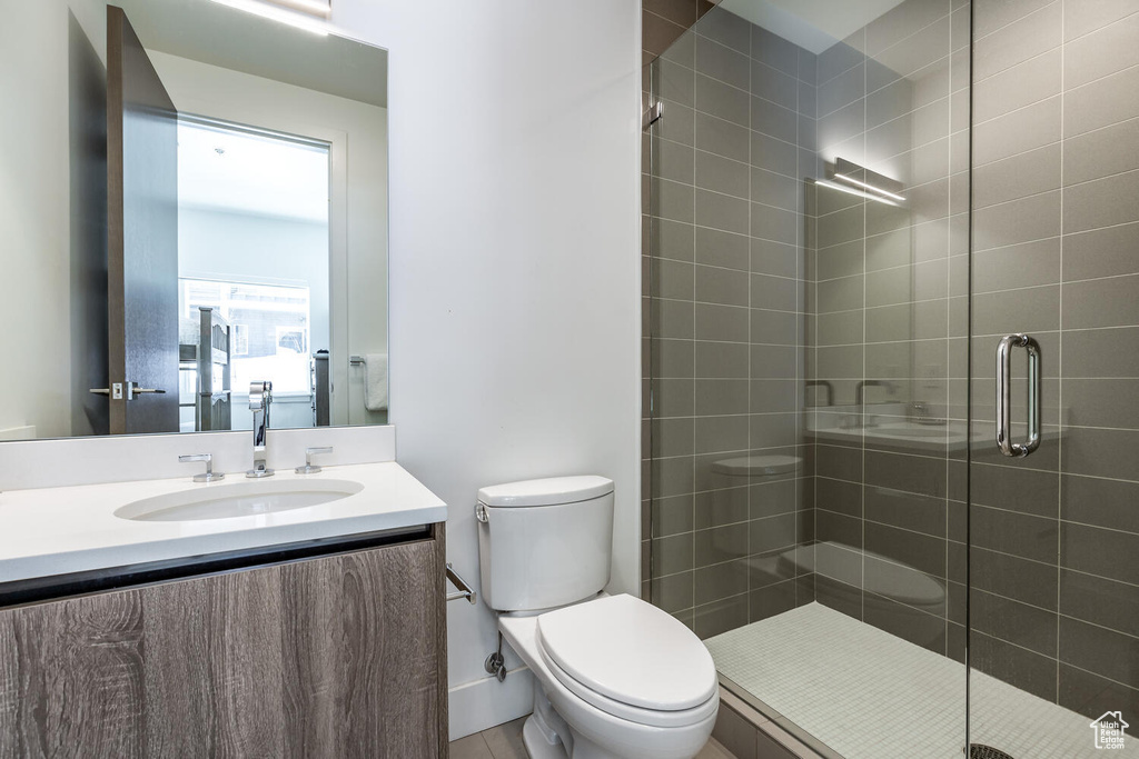 Bathroom with a shower with door, vanity, and toilet