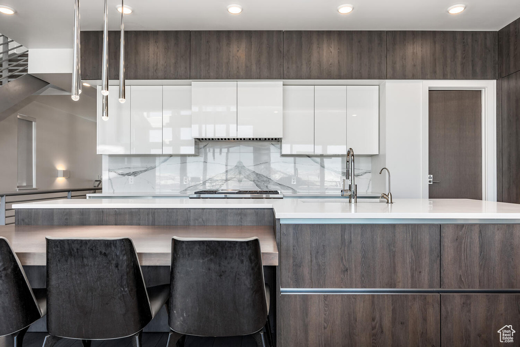 Kitchen with sink, white cabinets, tasteful backsplash, and stainless steel gas cooktop