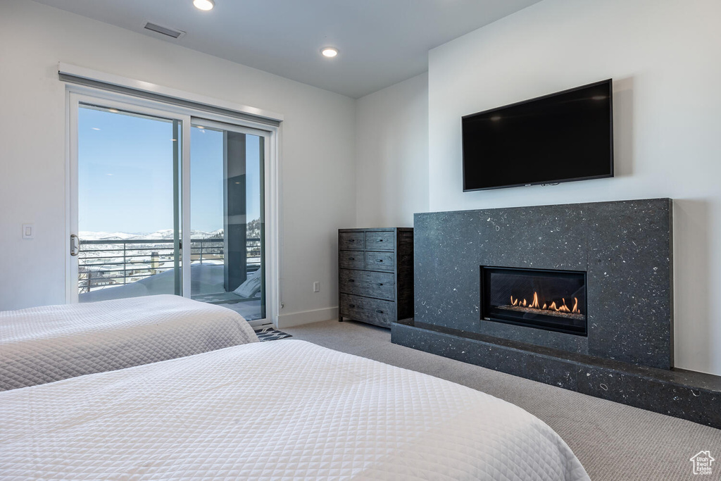 Bedroom featuring carpet, a fireplace, and access to outside