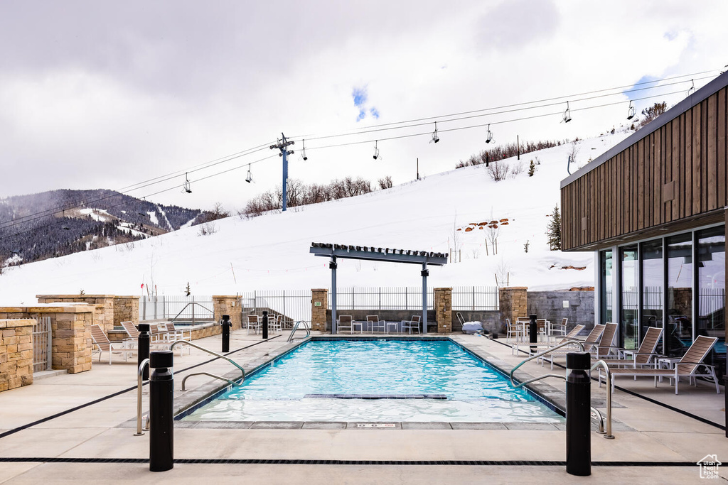 Snow covered pool with a patio area and a mountain view