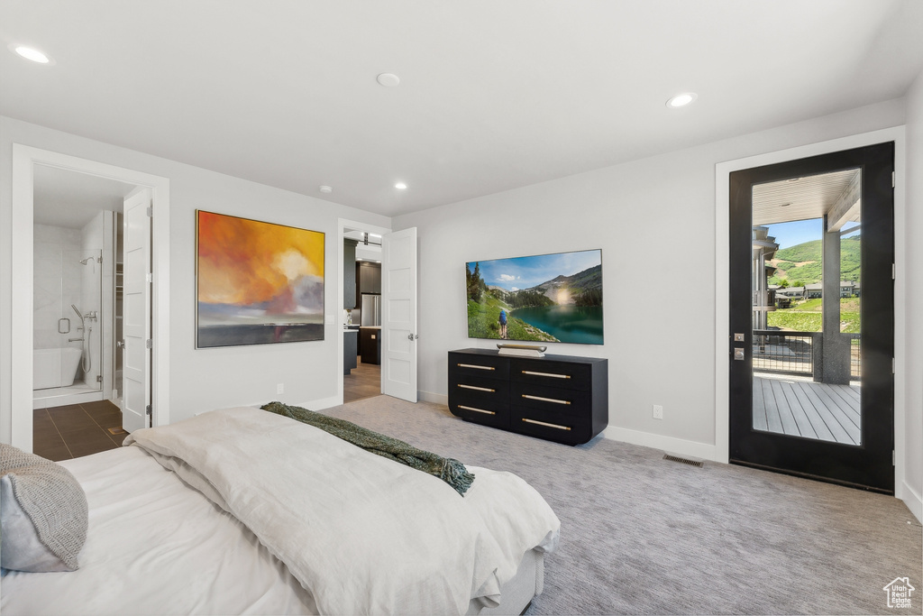 Bedroom with carpet, ensuite bathroom, and access to exterior