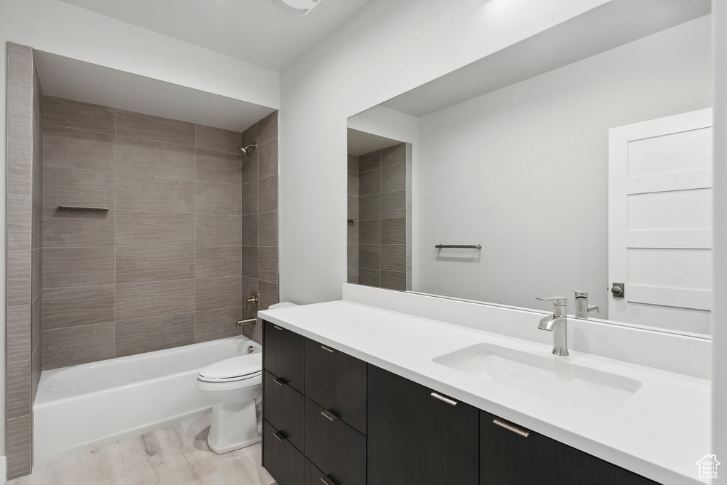 Full bathroom with tiled shower / bath, vanity, toilet, and wood-type flooring