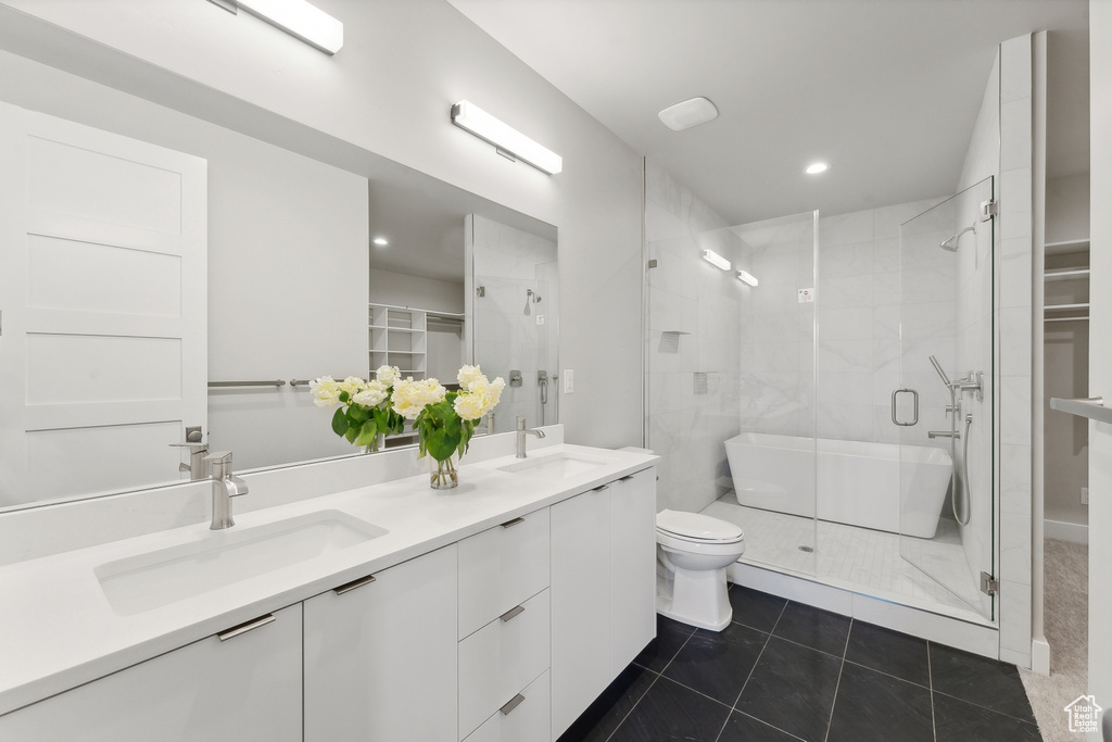 Bathroom with tile flooring, walk in shower, toilet, and double vanity