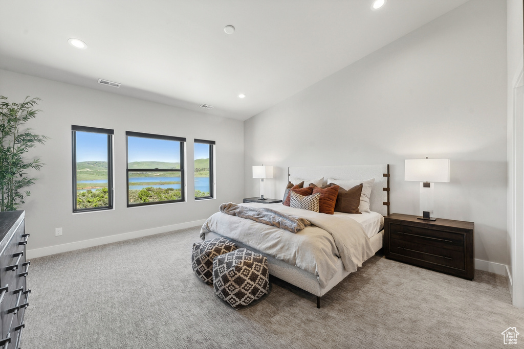 Carpeted bedroom featuring vaulted ceiling and a water view