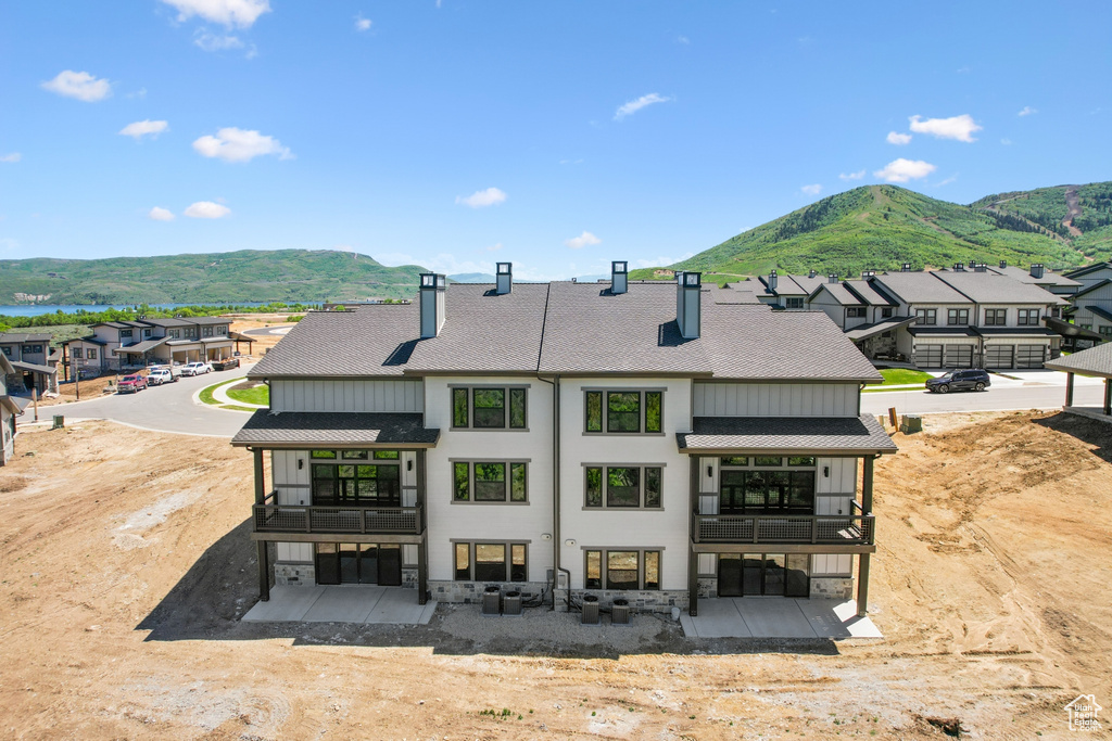 Rear view of property featuring a garage, a mountain view, a balcony, and a patio