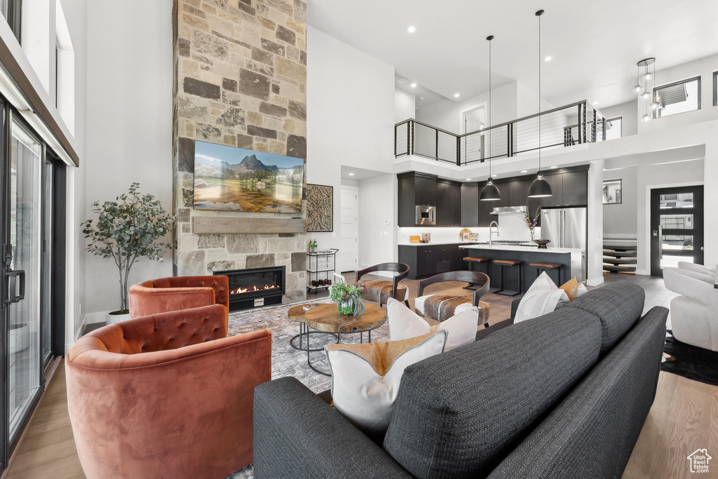 Living room featuring a high ceiling, a stone fireplace, and light hardwood / wood-style floors