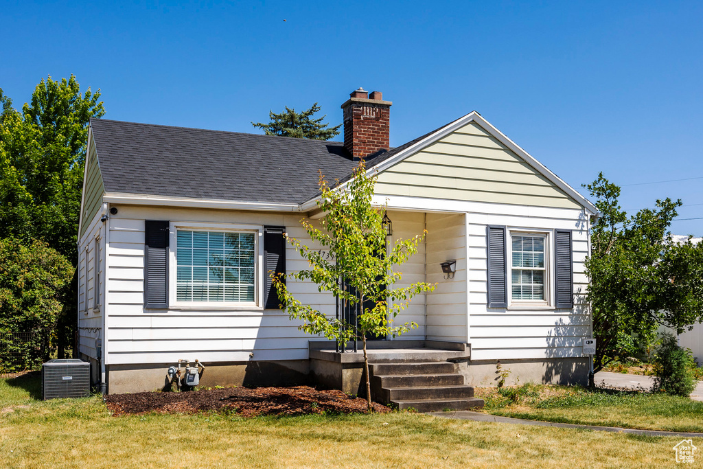 Bungalow-style house featuring central air condition unit and a front yard