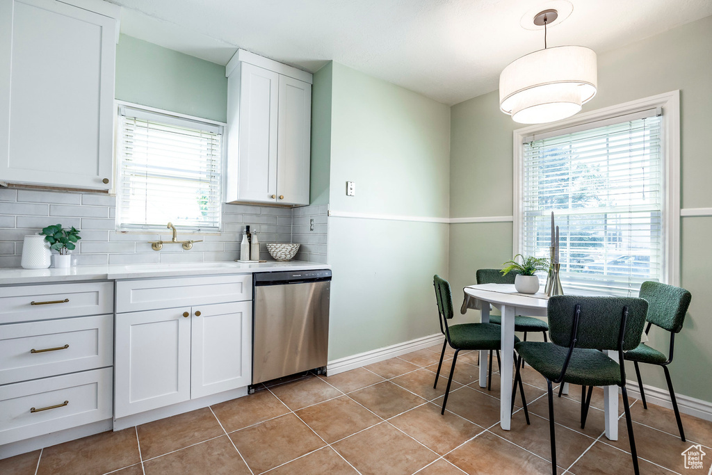 Kitchen with white cabinetry, backsplash, decorative light fixtures, sink, and stainless steel dishwasher