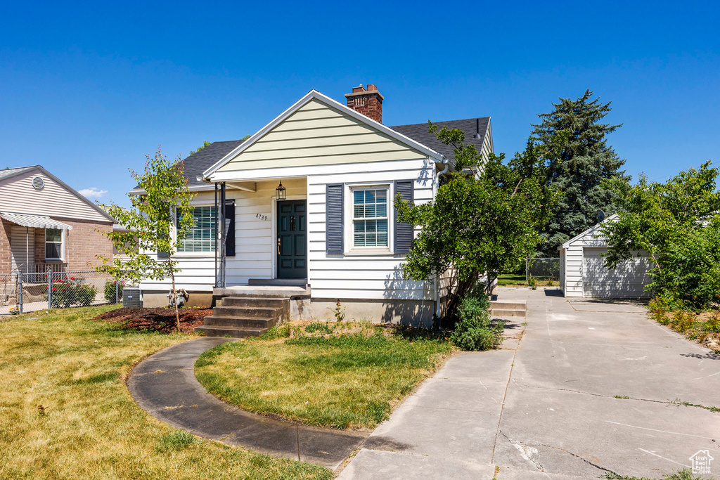 View of front of home with an outbuilding, a garage, and a front lawn