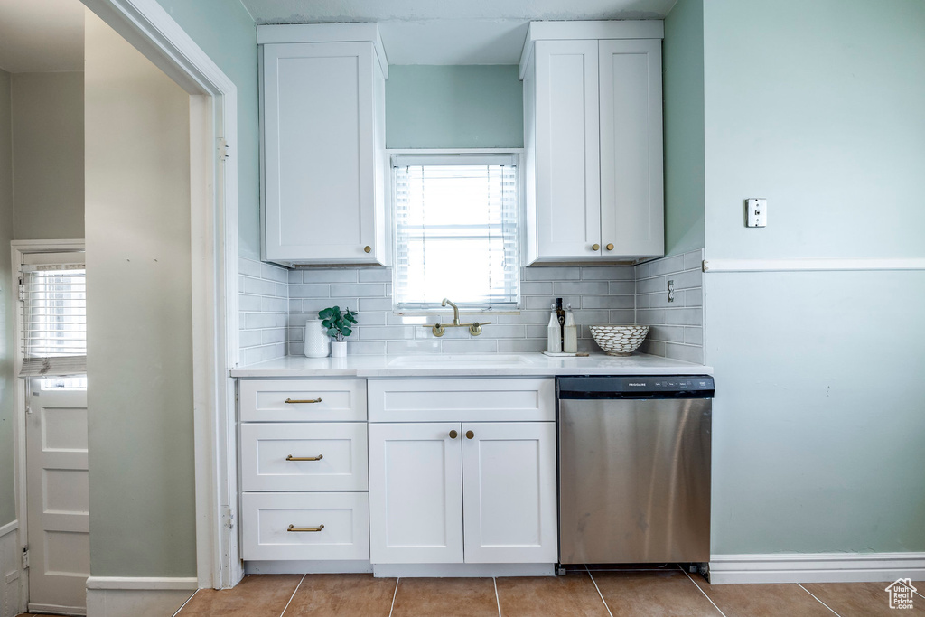 Kitchen with white cabinetry, a wealth of natural light, stainless steel dishwasher, and sink