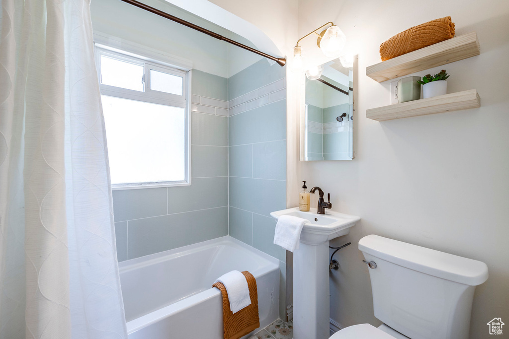 Bathroom featuring plenty of natural light, toilet, and shower / bath combo