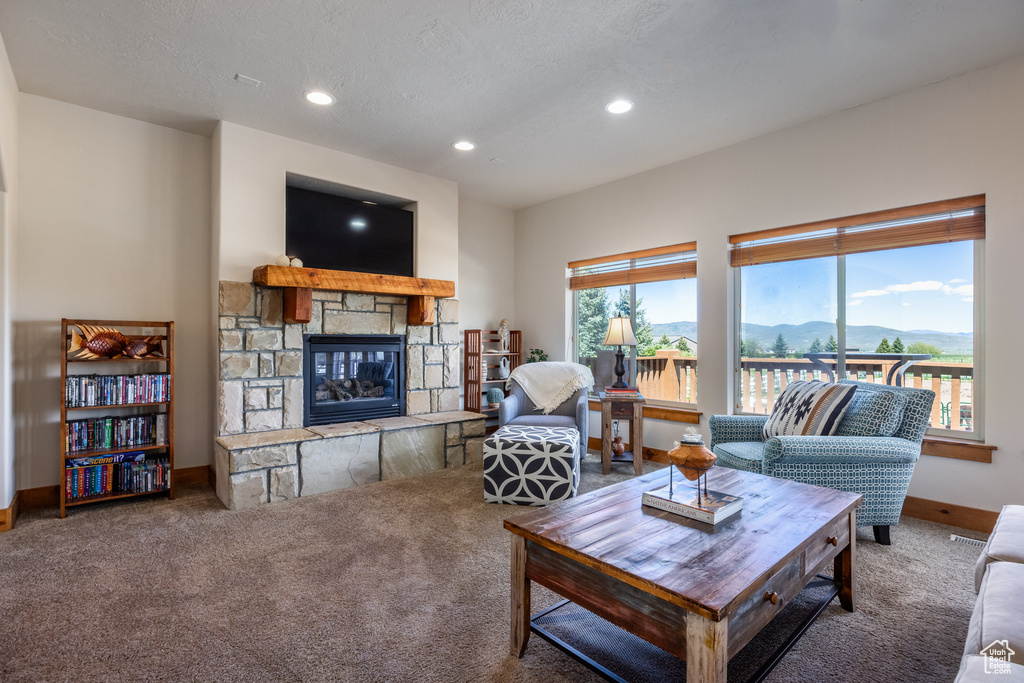 Living room with a textured ceiling, carpet flooring, and a fireplace