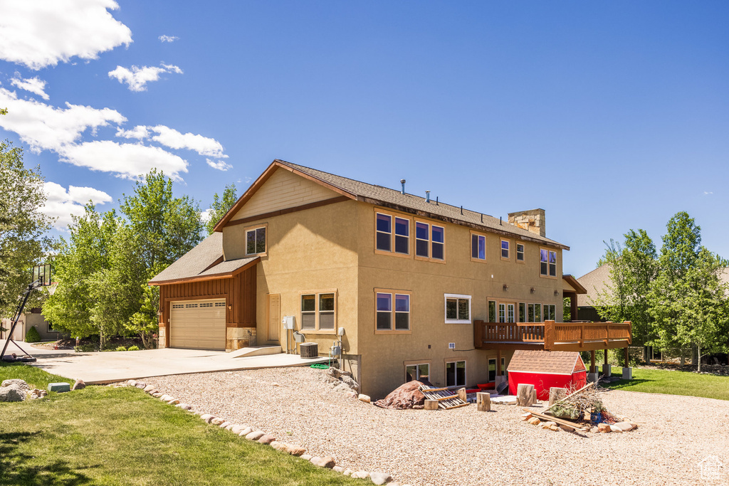 View of front of property featuring a front yard, central AC unit, and a wooden deck