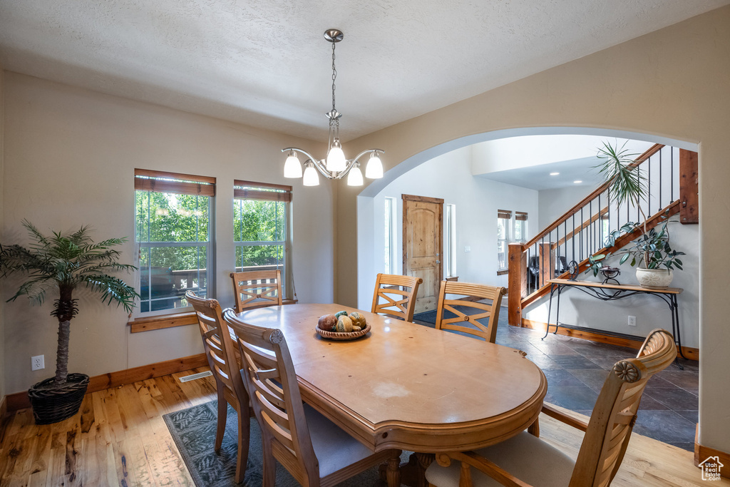 Dining area featuring wood-type flooring, a chandelier, and a textured ceiling