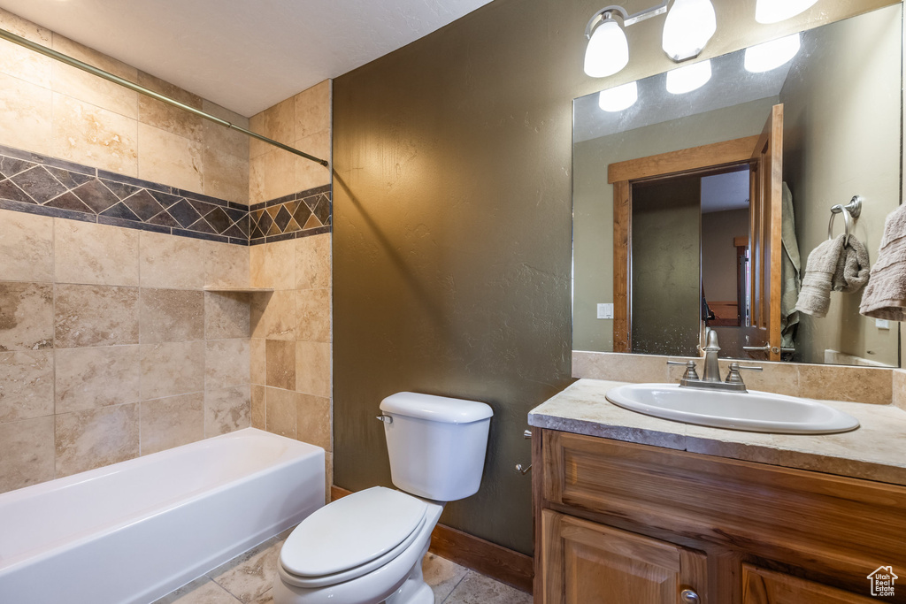 Full bathroom with tile patterned flooring, toilet, vanity, and tiled shower / bath